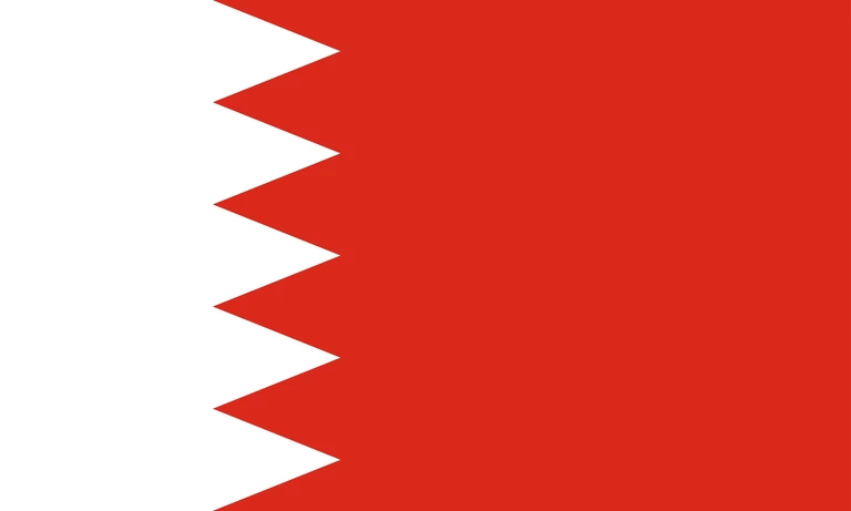 The flag of Bahrain has a red field. On the hoist side, it features a white vertical band that spans about one-third the width of the field and is separated from the rest of the field by five adjoining fly-side pointing white isosceles triangles that serve as a serrated line.